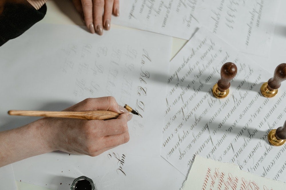 una mano realiza lettering sobre papeles