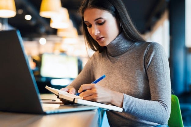 Mujer escribiendo en frente a la computadora