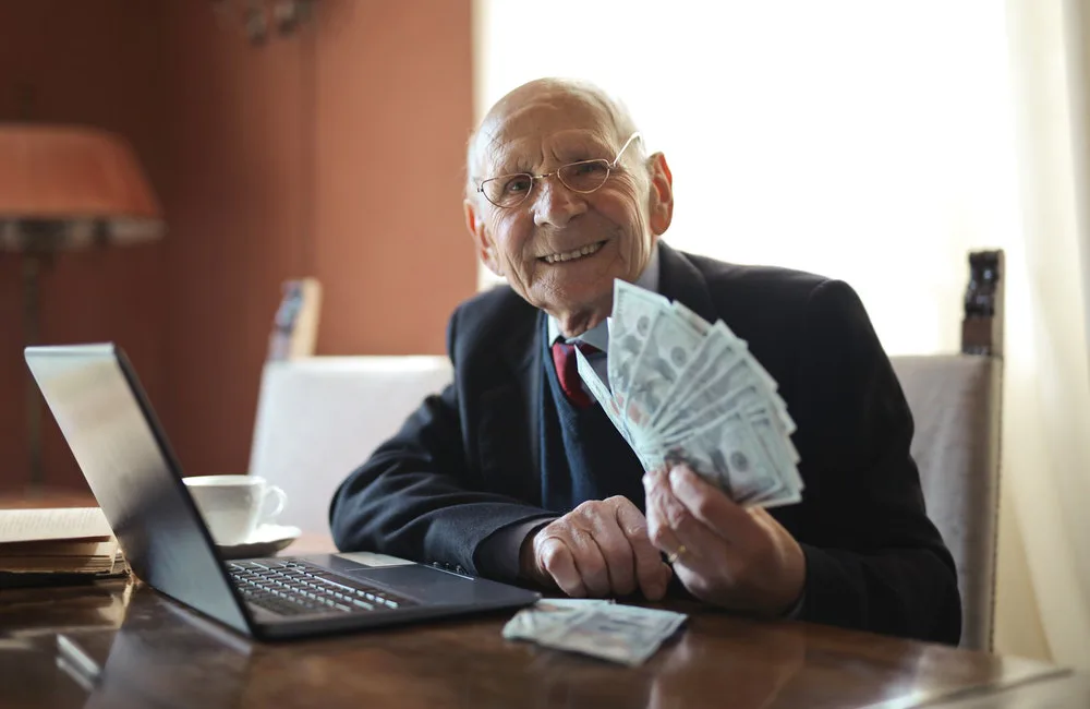 un hombre sentado en un escritorio sostiene billetes