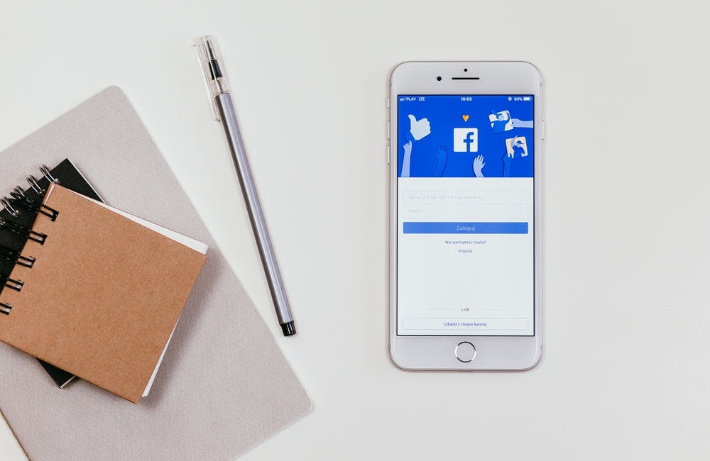 un celular proyecta el logo de facebook y material de librería
