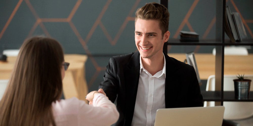 reclutador estrechando la mano a una candidata en una entrevista de trabajo