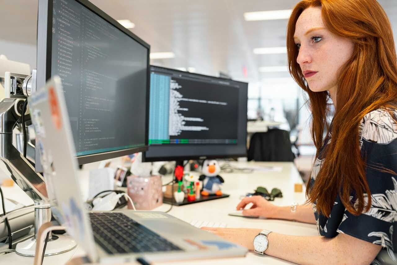 mujer consulta los distintos tipos de bases de datos de la compañía en su mesa de trabajo
