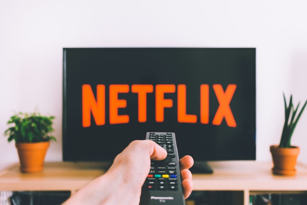 persona seleccionando netflix con control remoto