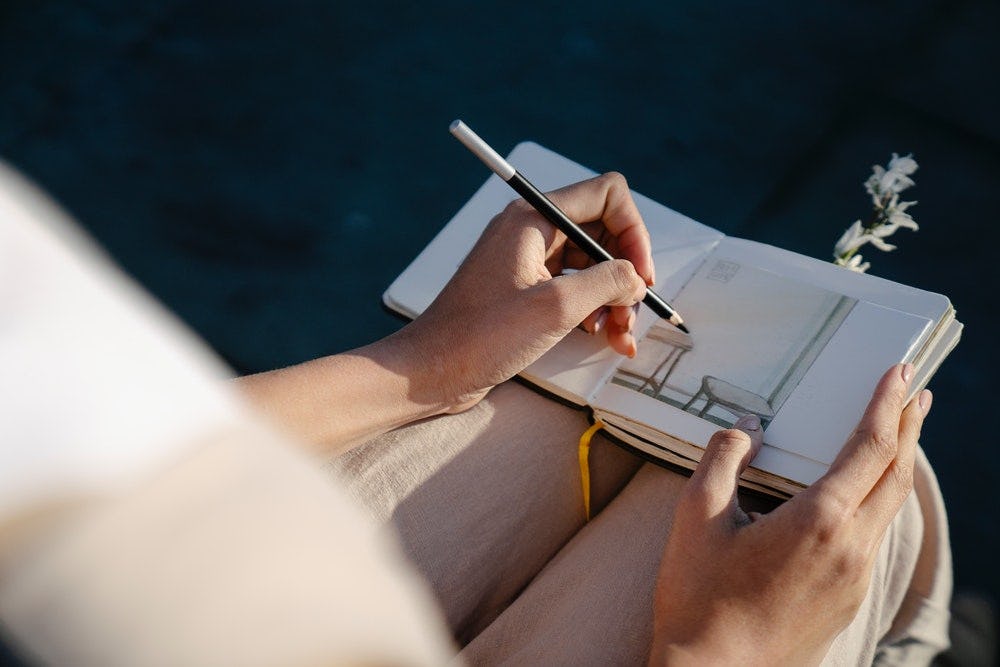 mujer dibujando muebles en un sketchbook al atardecer