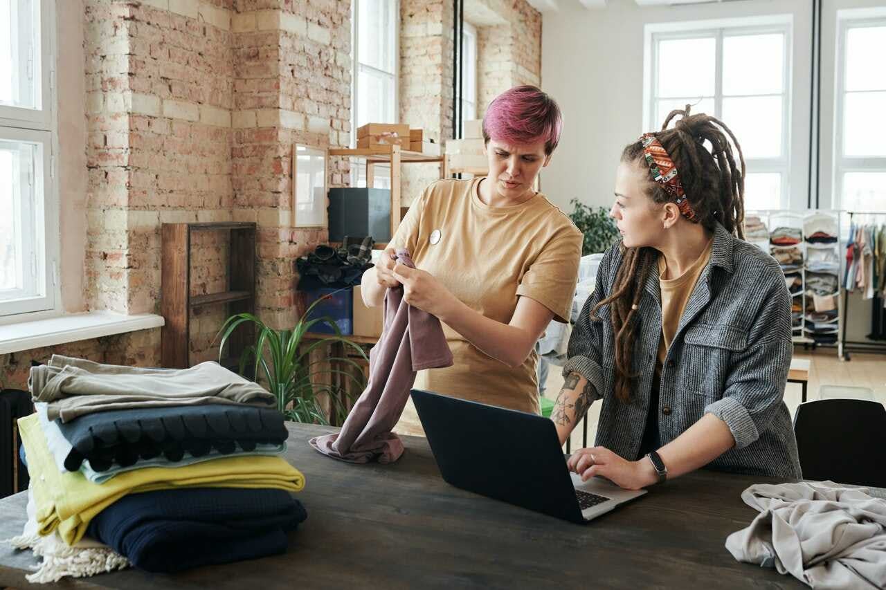 socias de una marca de ropa elaboran un plan de promoción en su taller con una laptop