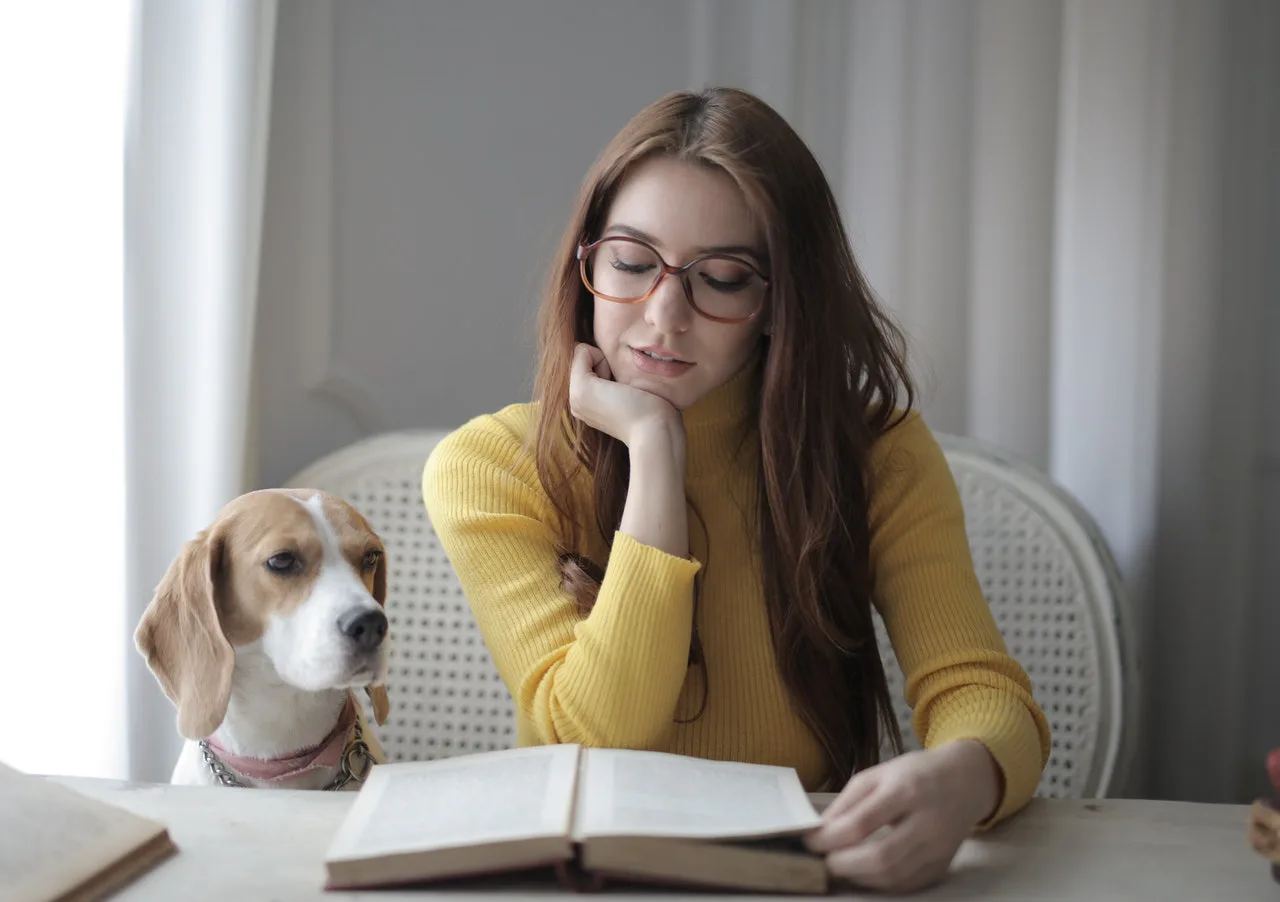mujer leyendo un libro junto a su perro