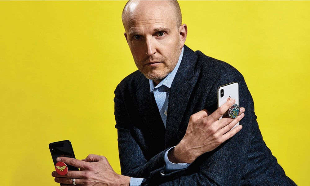 David Barnett sosteniendo teléfonos móviles con popsockets