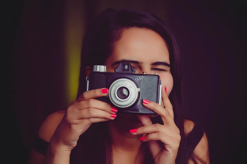 mujer tomando fotos con una camara vintage