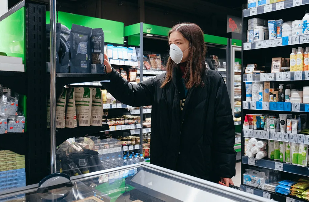 Joven haciendo compras en un supermercado, decidiendo que producto escoger.