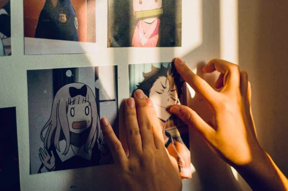 Persona colocando posters de animes en su pared
