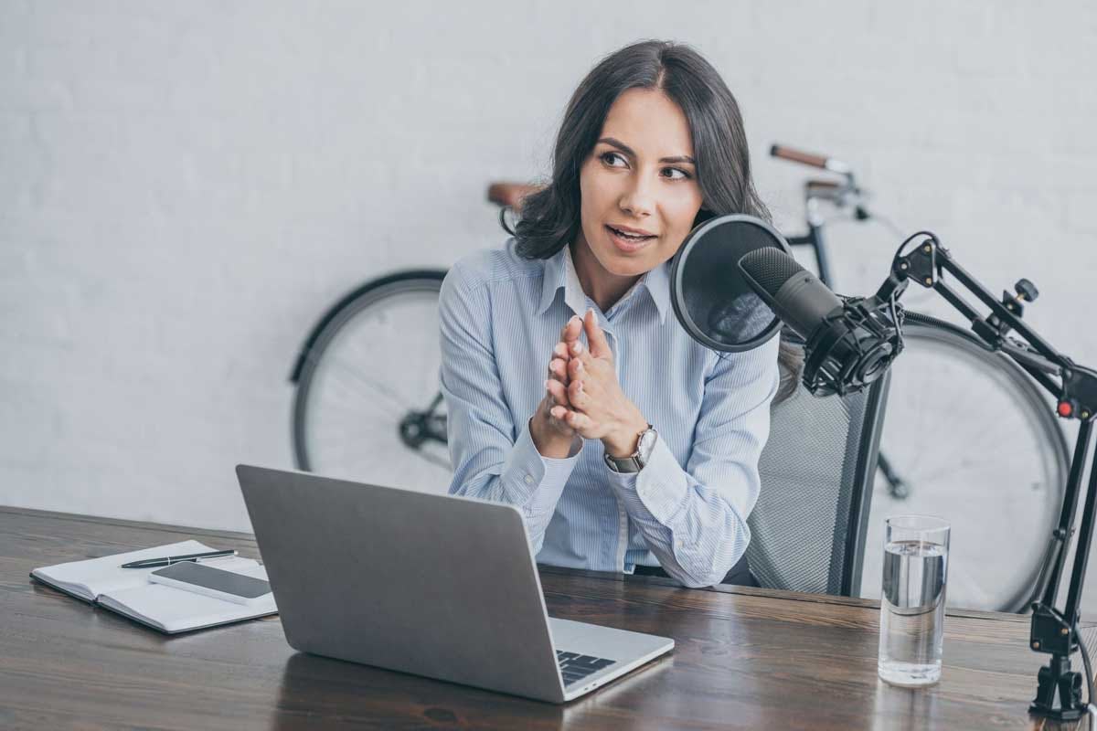 mujer con laptop y micrófono grabando podcast