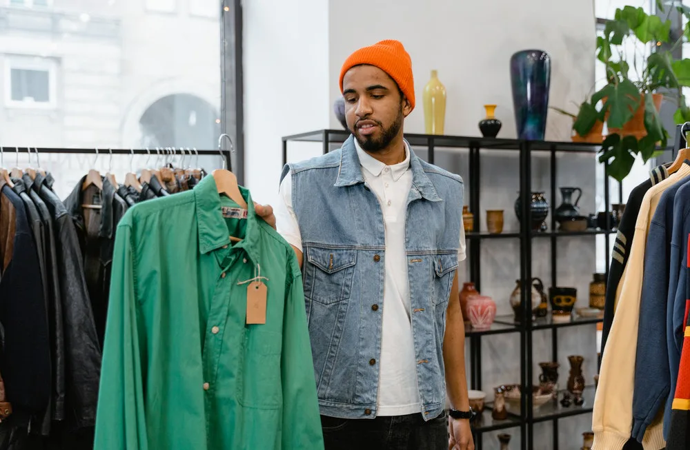 Joven escogiendo diferentes camisas de diversas marcas.