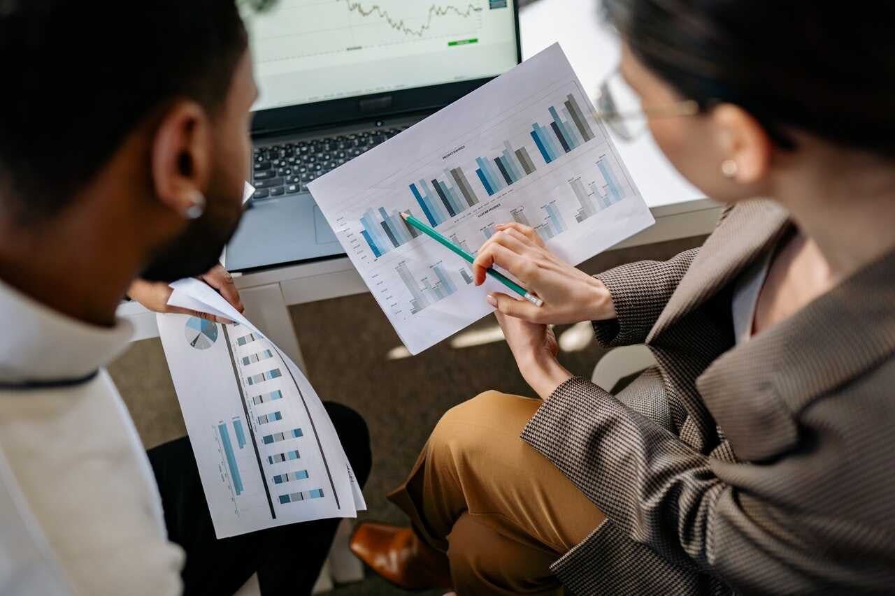 compañeros de trabajo realizan una base de datos multidimensional para la empresa a partir de informes en una laptop