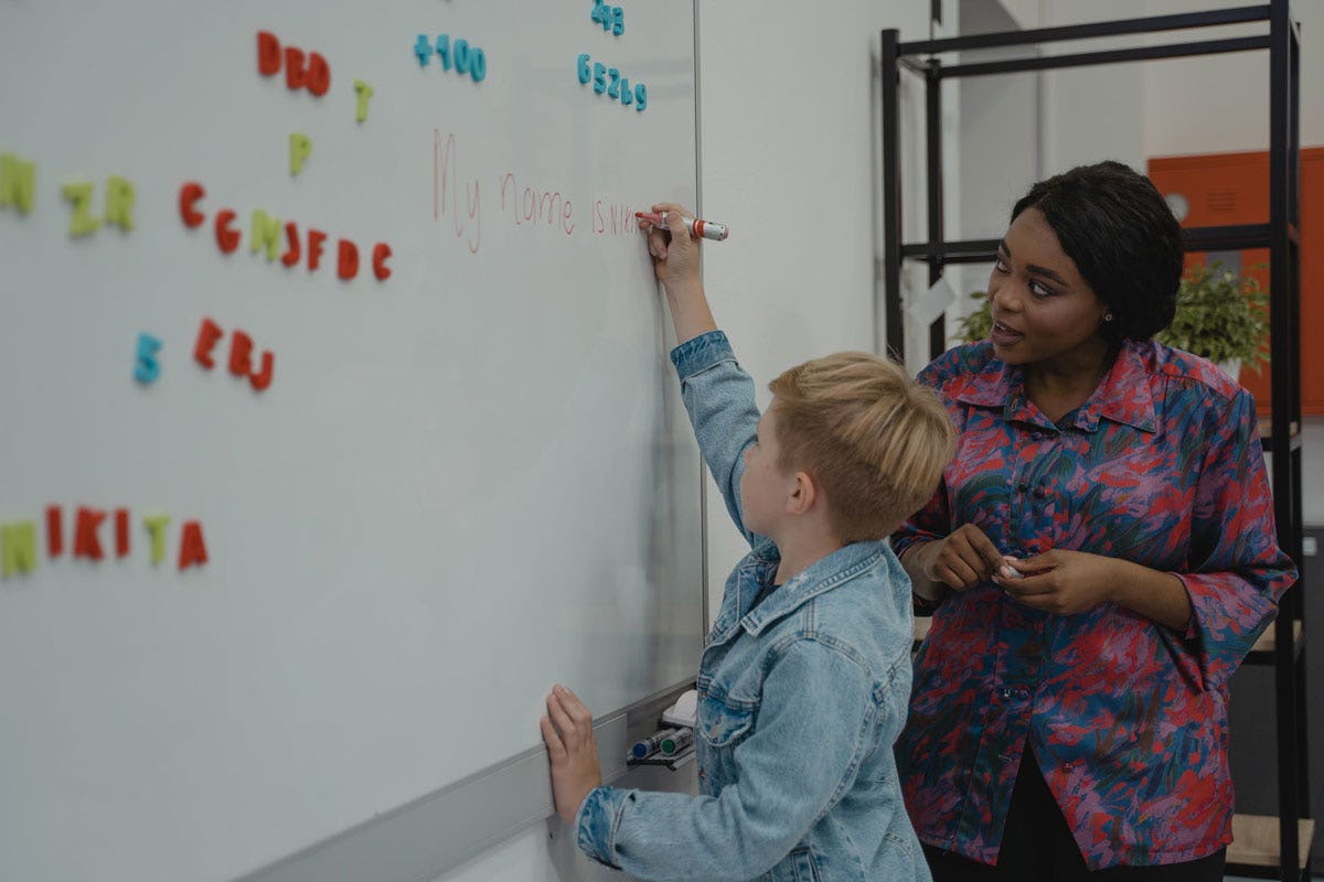 Niño escribiendo en pizarrón blanco en clases de inglés