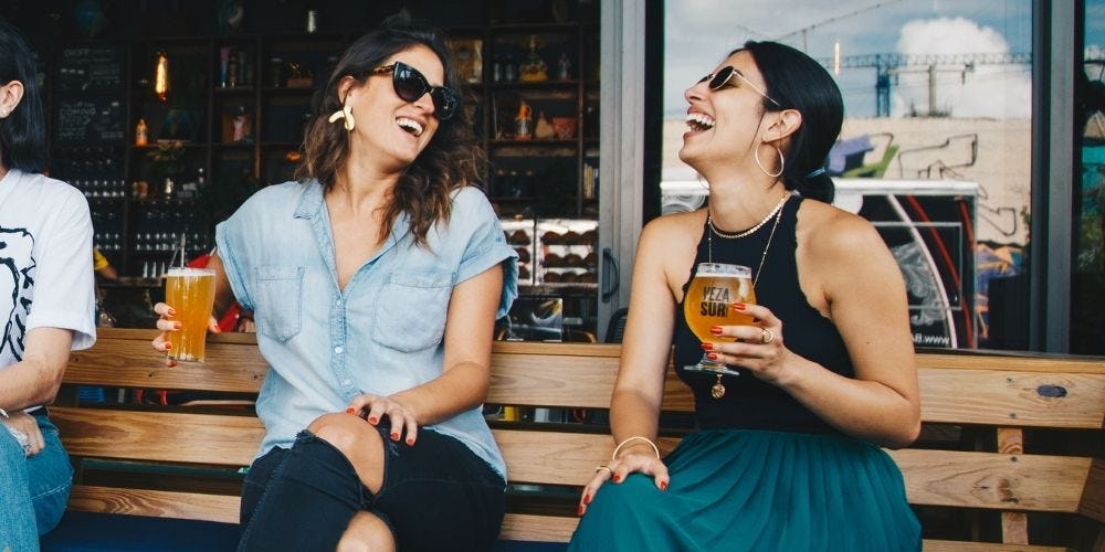Dos mujeres riendo de un chiste sobre trabajo
