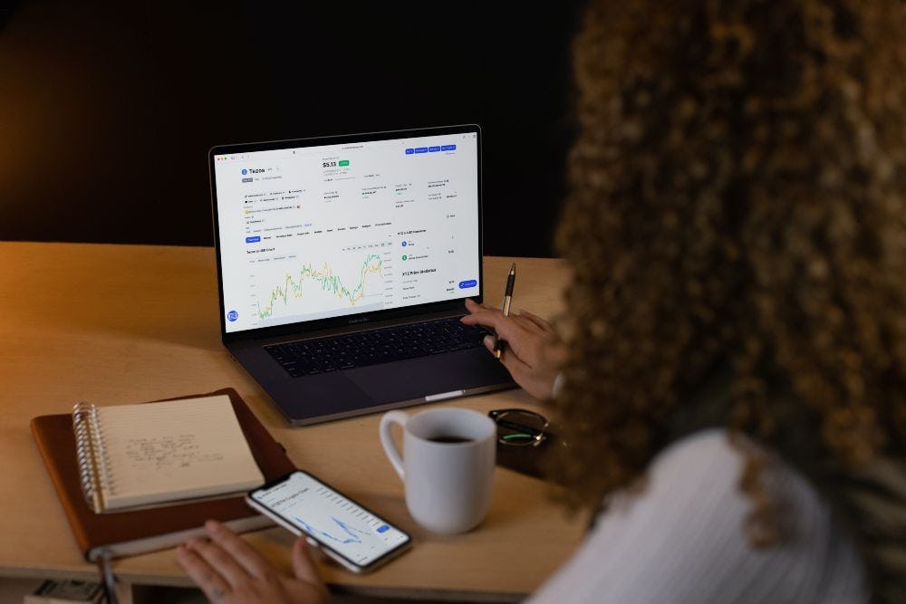 mujer frente a computador con graficos criptomonedas