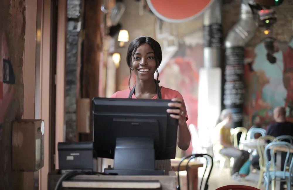 una mujer sonríe frente a un computador en un comercio