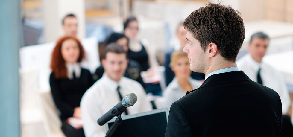 Persona hablando en público con técnica vocal adecuada
