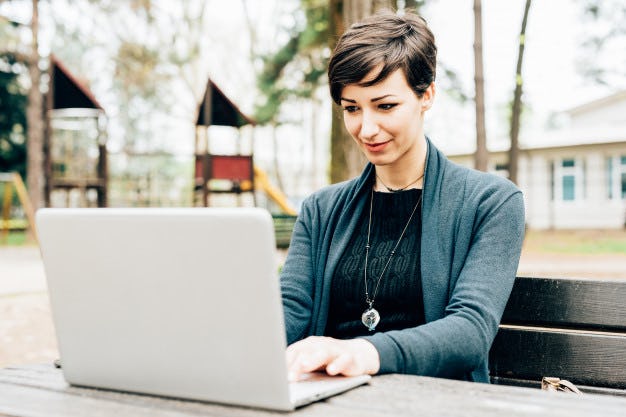 Mujer trabajando afuera de su casa con la computadora en su emprendimiento digital