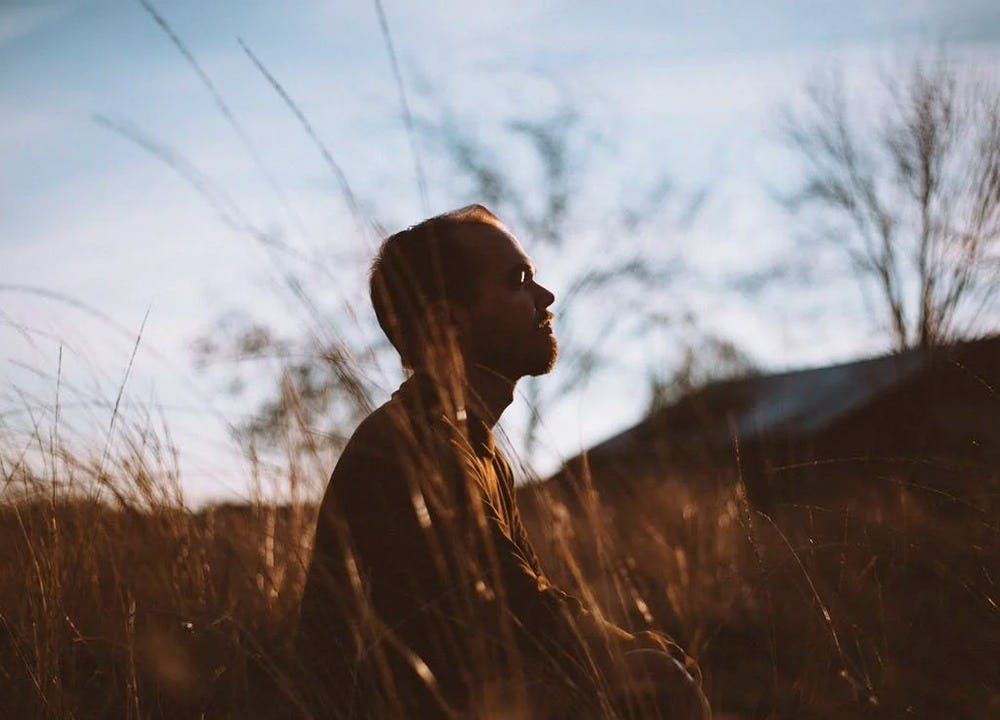 hombre persona resiliente meditando en pradera