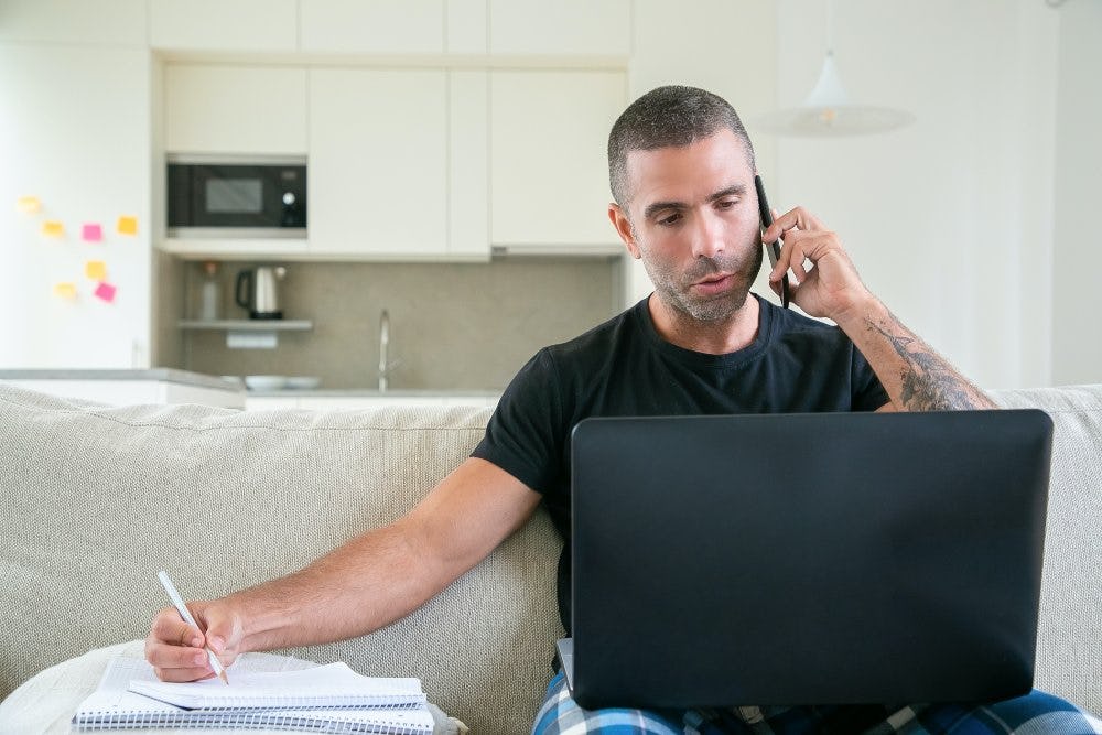 hombre hablando por celular y mirando al computador