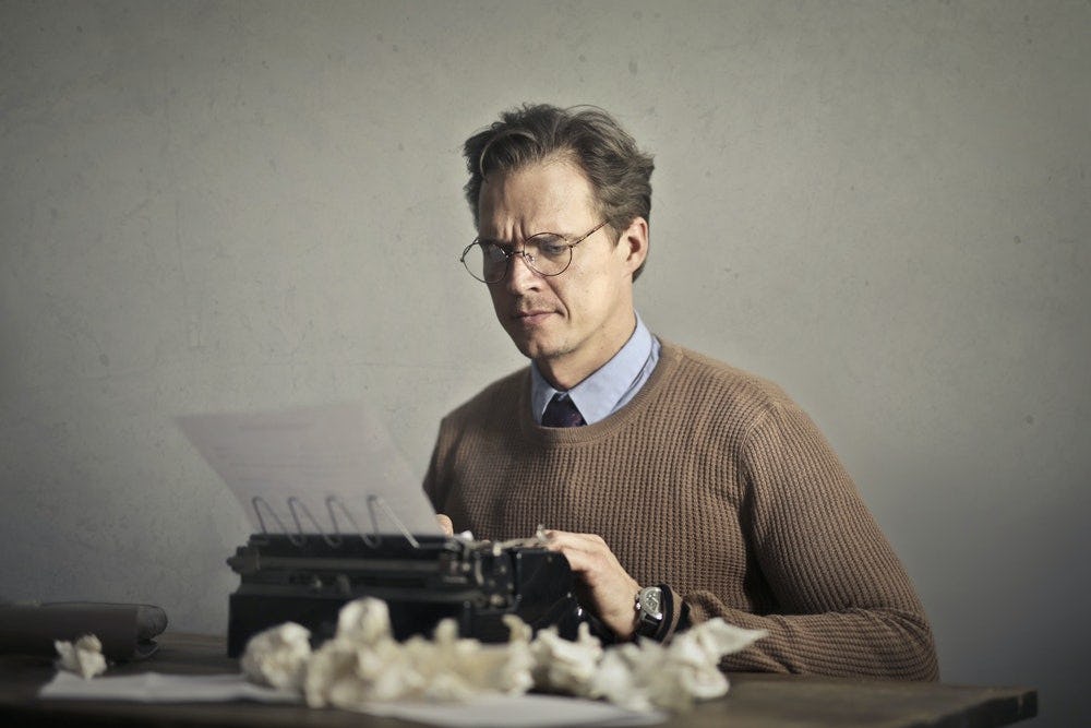 hombre usando maquina para escribir un libro