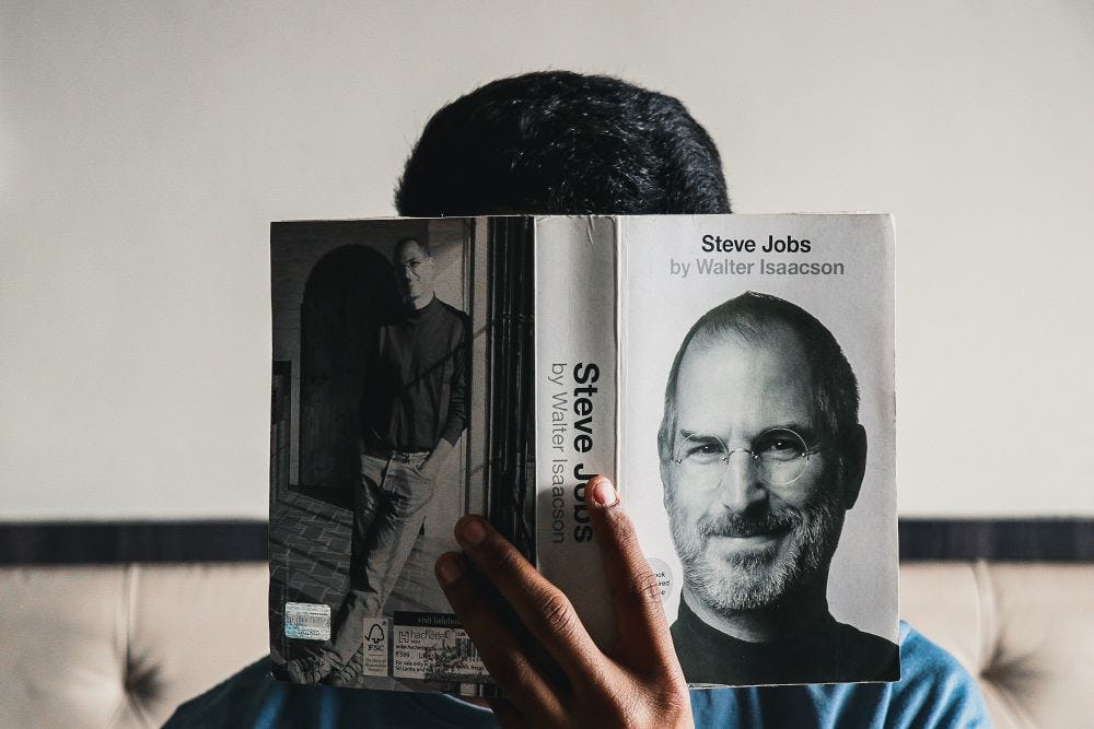 hombre leyendo un libro de Steve Jobs